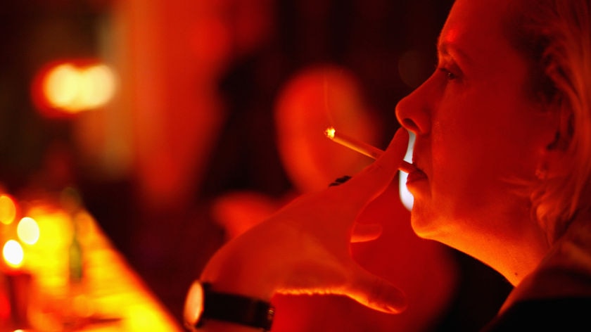 A woman smokes a cigarette inside the Parallelwelt bar in the Altona district in Hamburg, Germany