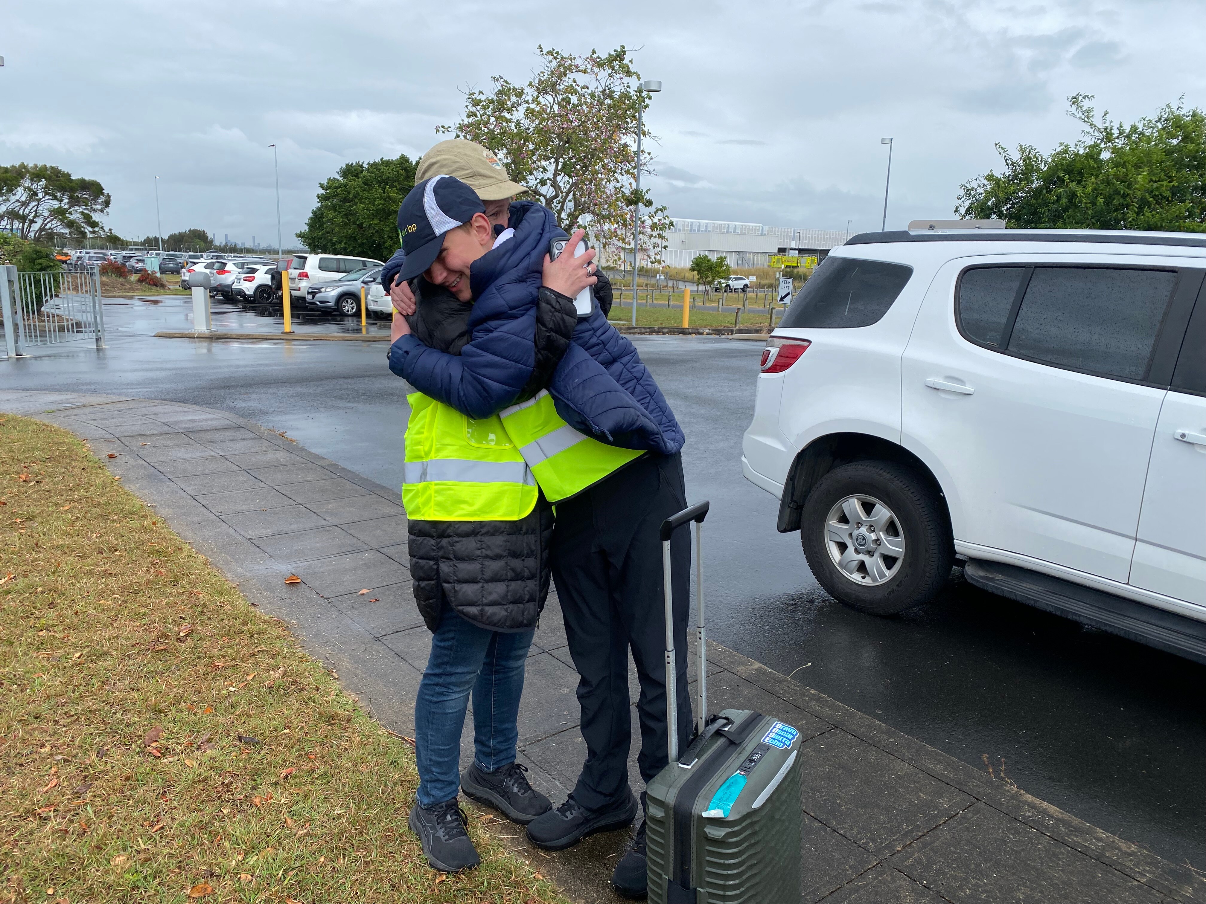 A mum hugs her son while both in highvis vests and rain jackets