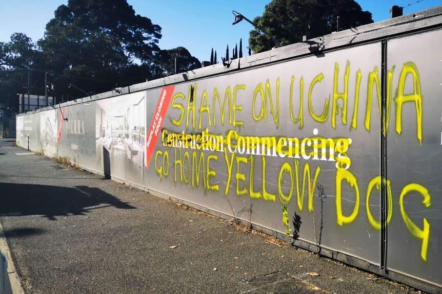 Graffiti in yellow letters reads: 'Shame on China, Go home yellow dog'.