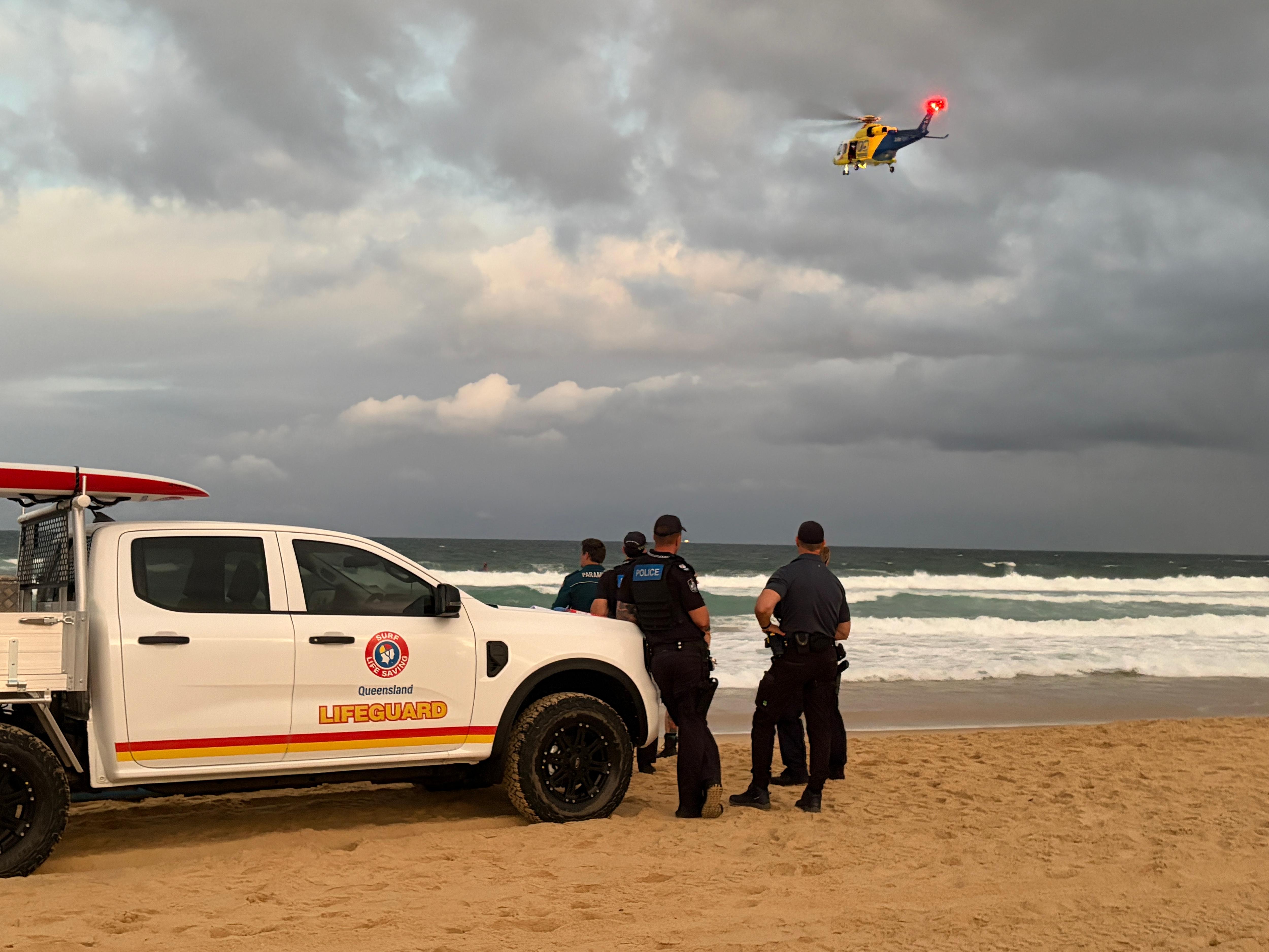LIfeguards beside ute as helicopter flies overhead over water