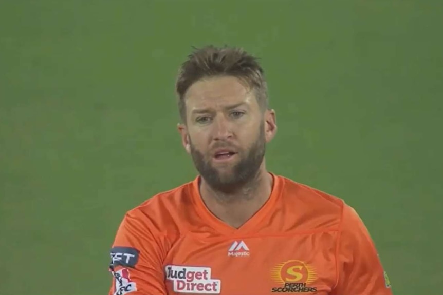 AJ Tye looks forwards with his mouth slightly open, while wearing an orange shirt