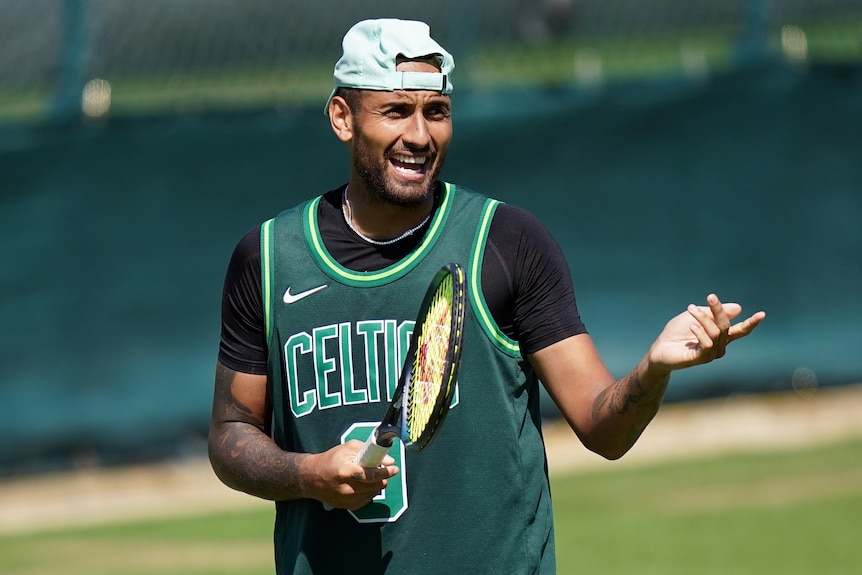 Nick Kyrgios holds a racket and gestures