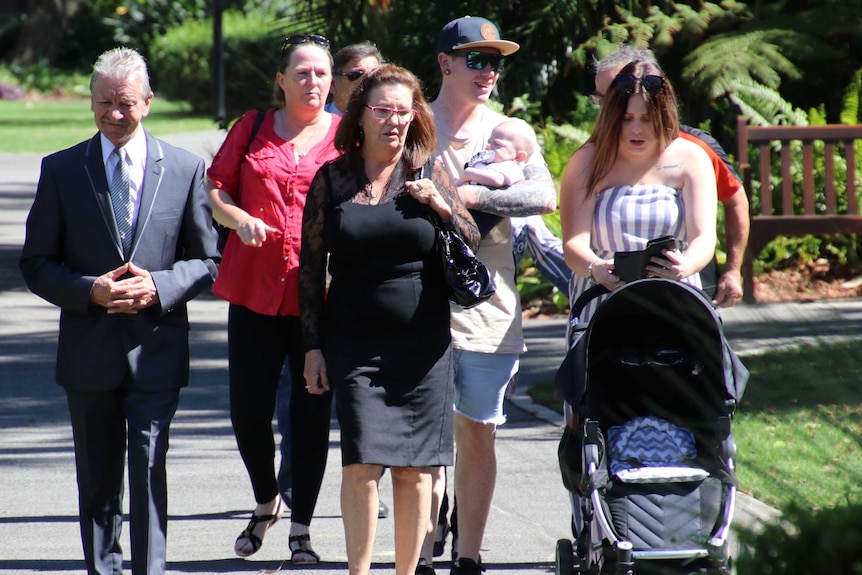 Group pic of Margaret Dodd and family members walking along a path in the Supreme Court Gardens Perth.