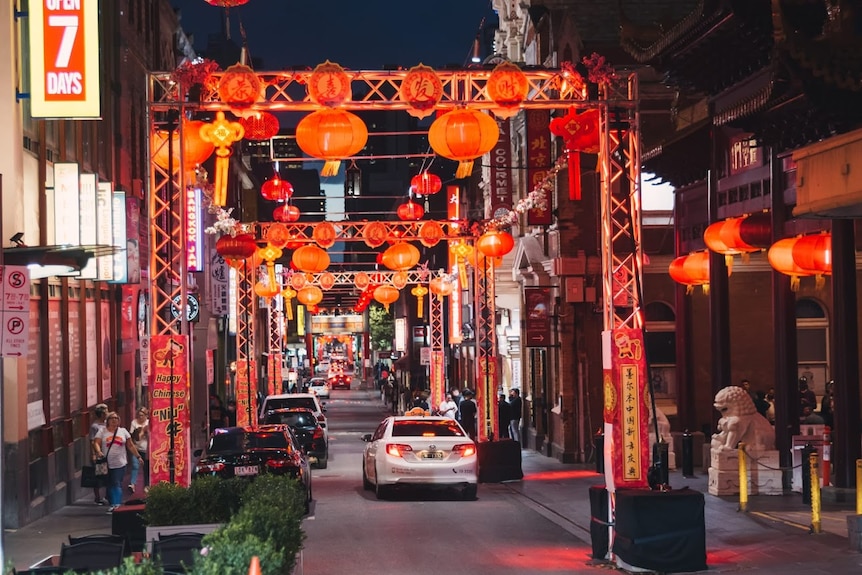 A street at night, lit up by a number of red Chinese lanterns on temporary scaffolding