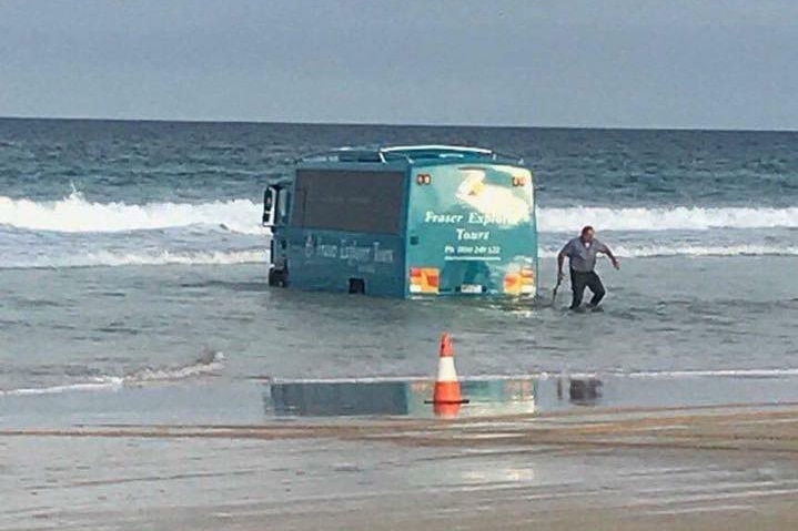 A bus bogged on a Fraser Island beach after attempting to help rescue a stranded plane.