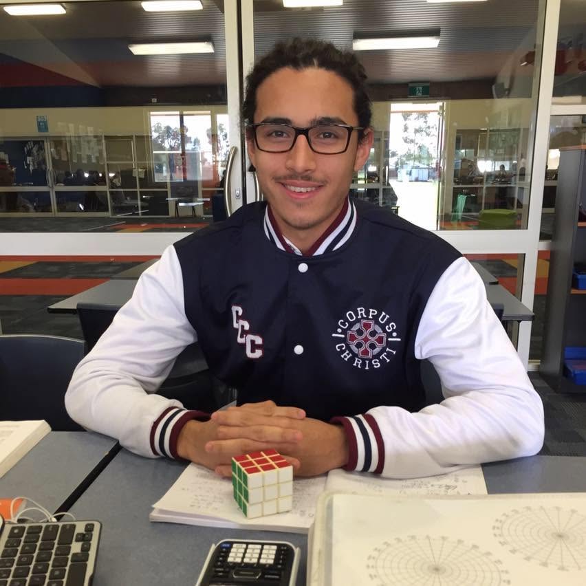 A boy who wears senior high school uniform sits at a desk. 