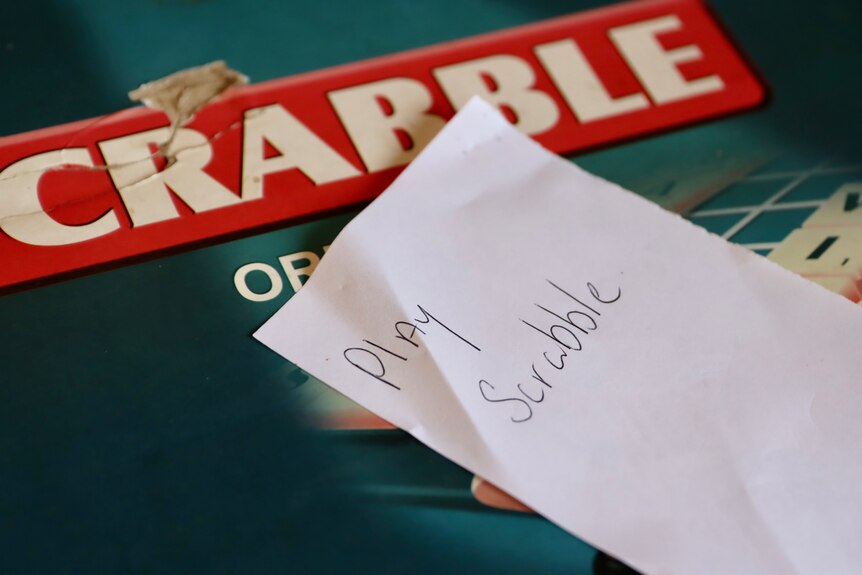 a scrabble box with a hand-written note saying "play scrabble" 