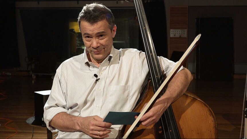 Edgar Meyer standing with his double bass and looking at the camera.