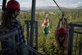 View from an elevated tower where two people are on a zipline.