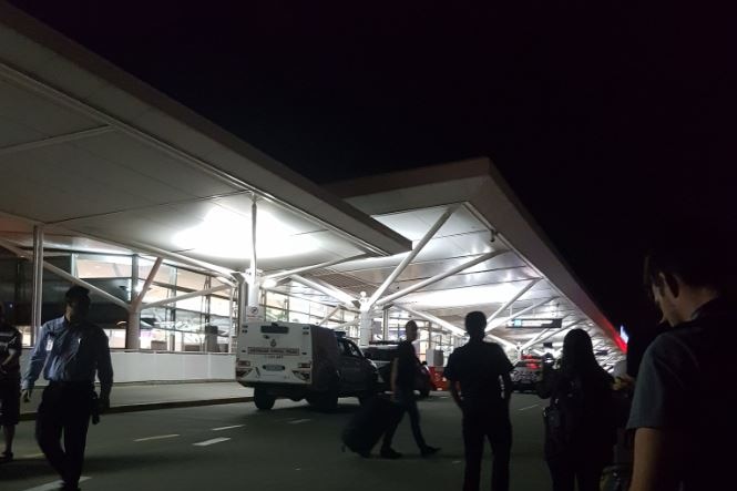 Police and members of the public gather outside the terminal entrance