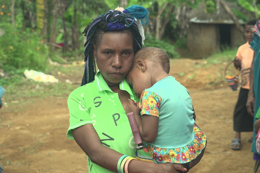PNG mother Alena Potape holds her child in her arms, both are wearing green