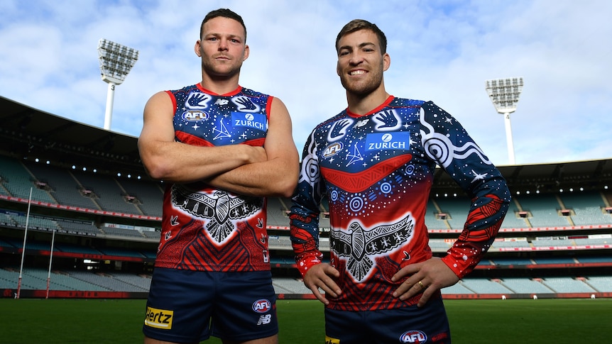Steven May and Jack Viney pose in the middle of the MCG wearing Melbourne's Indigenous round jersey