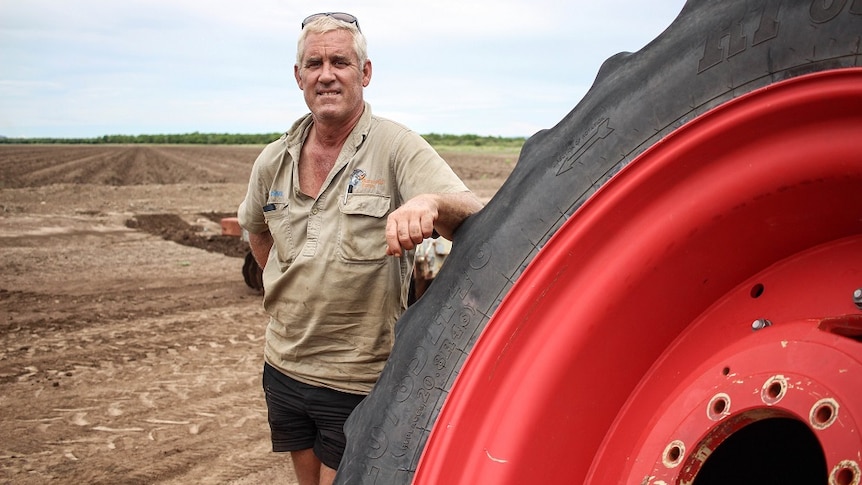 David Menzel leaning on a tractor wheel at his farm in Kununurra.
