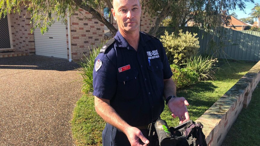 Illawarra Fire and Rescue Duty Commander Andrew Erlik holds melted butane heater in front of unit where a fire broke out