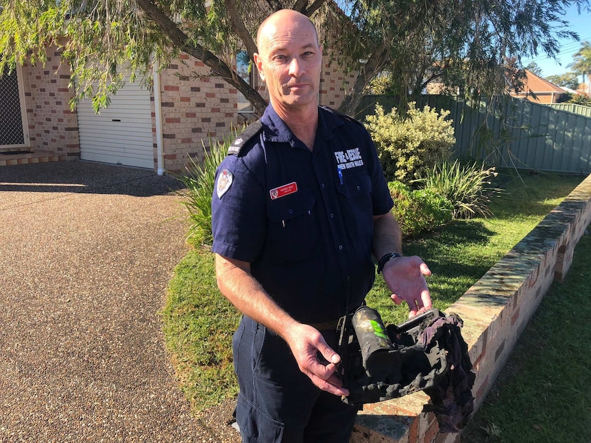 Illawarra Fire and Rescue Duty Commander Andrew Erlik holds melted butane heater in front of unit where a fire broke out
