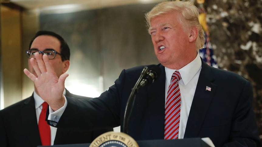 US President Donald Trump looks angry while speaking at his podium, his left hand up in front of him