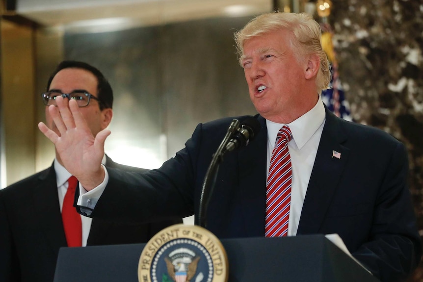 US President Donald Trump looks angry while speaking at his podium, his left hand up in front of him