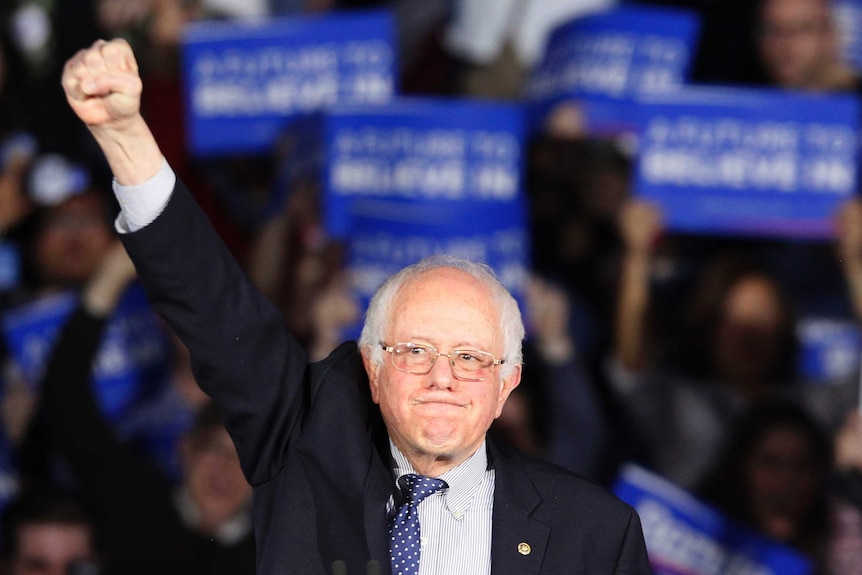 Bernie Sanders raises a fist as he addresses supporters.