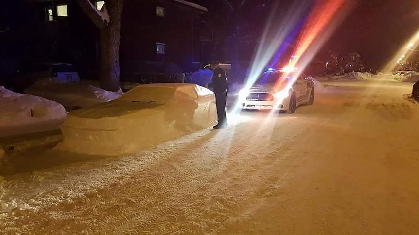 Police in Canada pull up next to a car made out of snow.