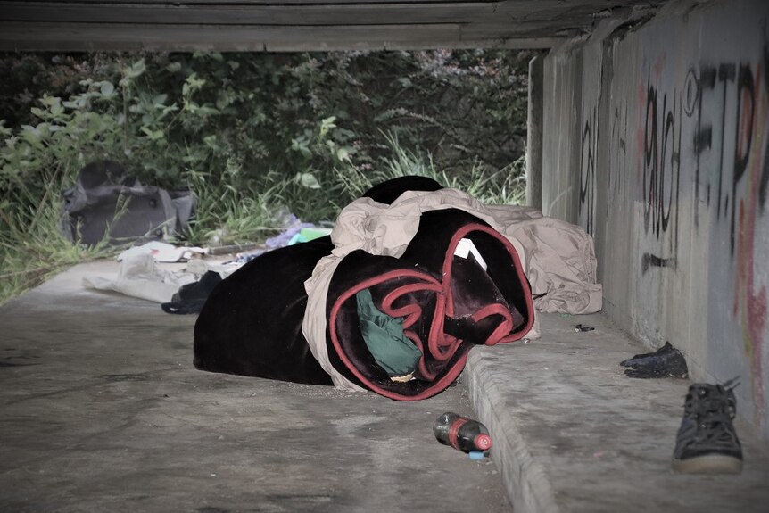 Blankets and sheets piled up under a bridge