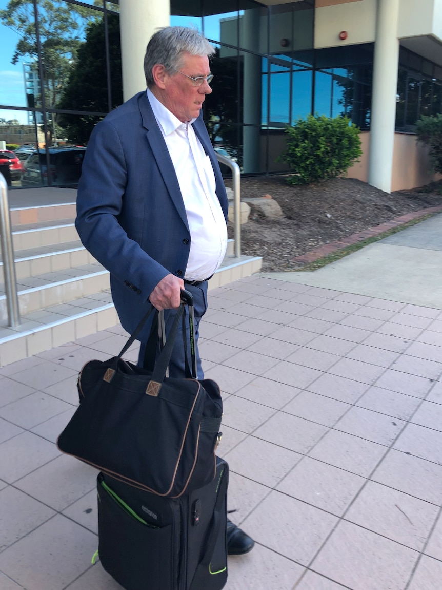 Man walking with luggage outside a court house