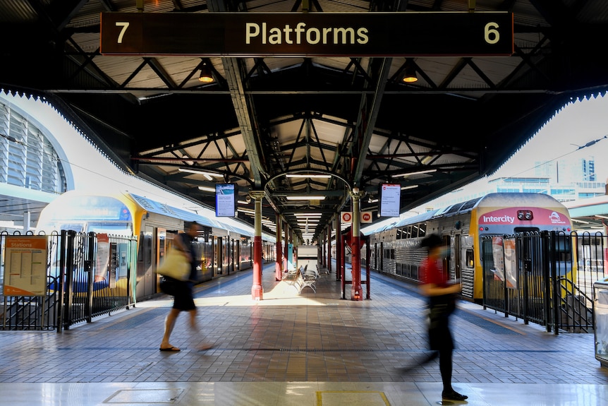 personas con máscaras y caminando por una plataforma de tren