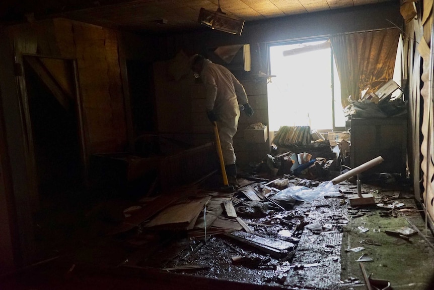A person walks among damaged property inside a home that was flooded.
