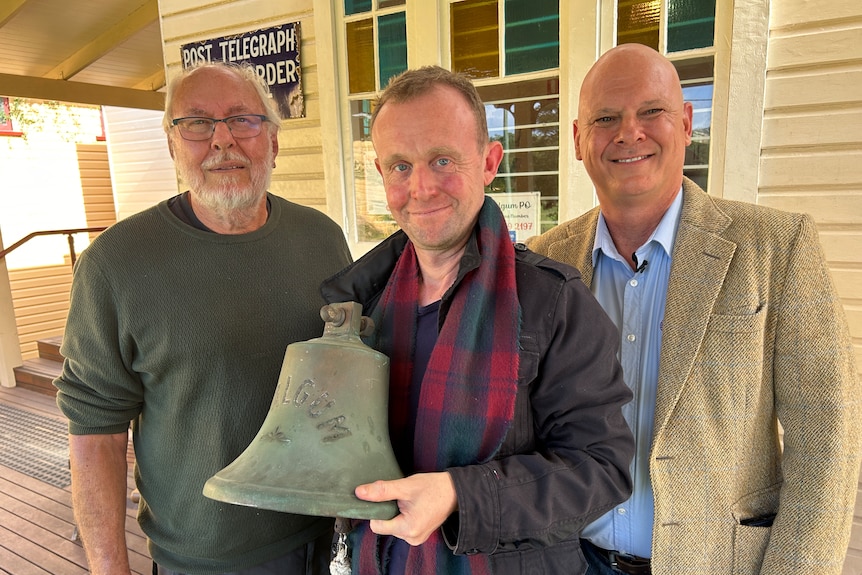 three men with old bell.