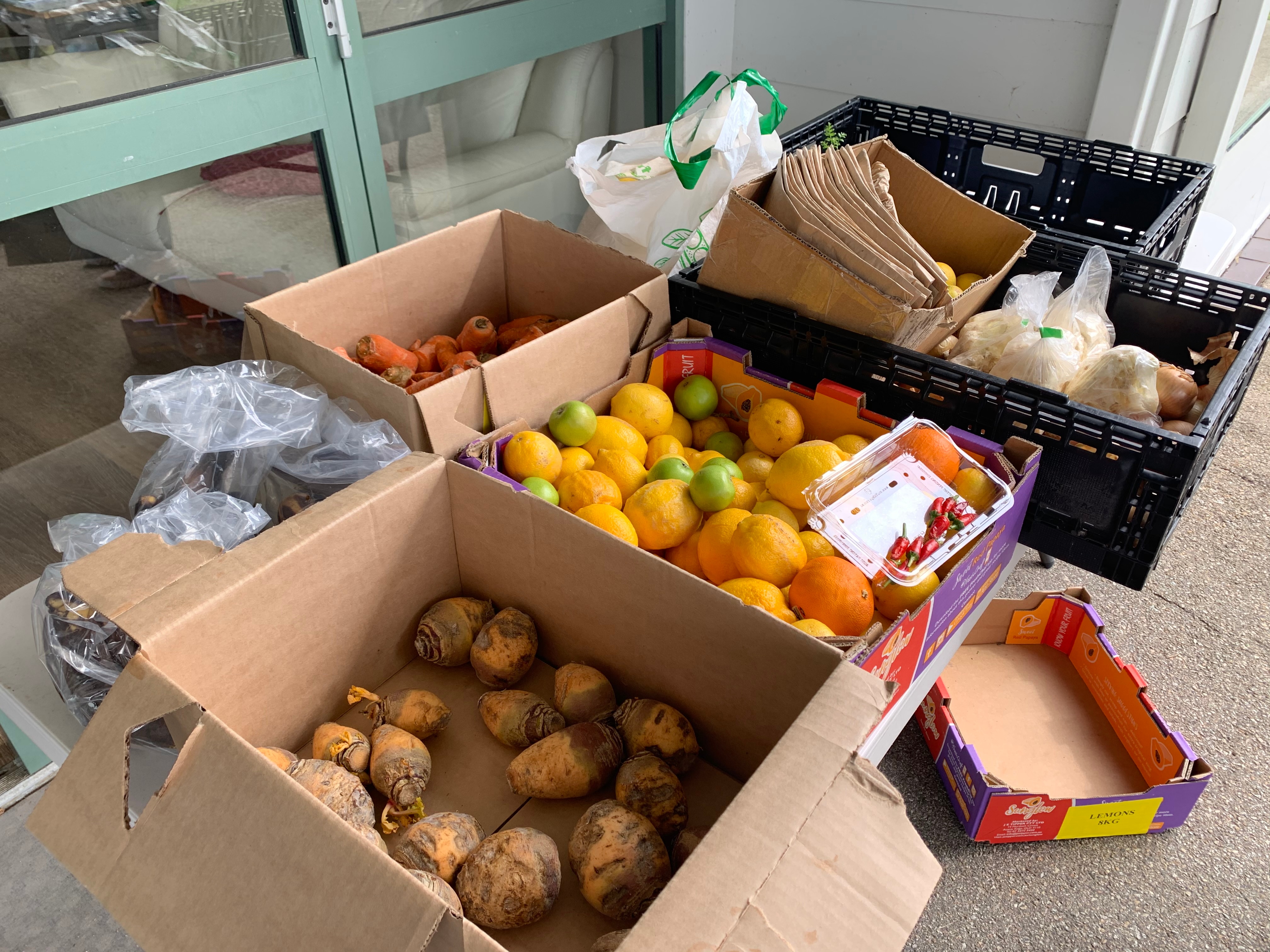 A box of fruit and vegetables on the trestle table.