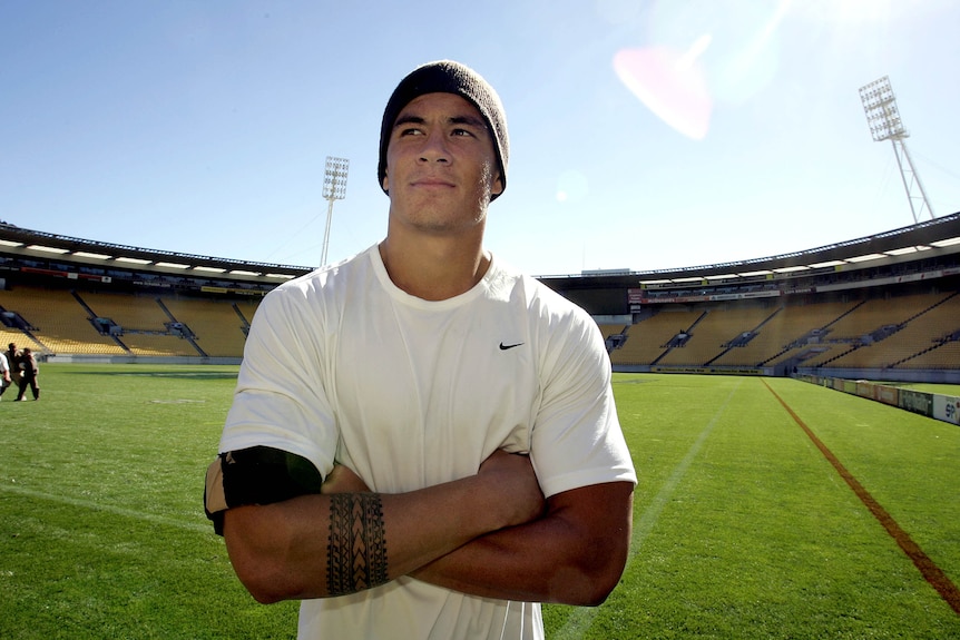 An 18-year-old Sonny Bill Williams crosses his arms and looks up while standing on an empty oval.