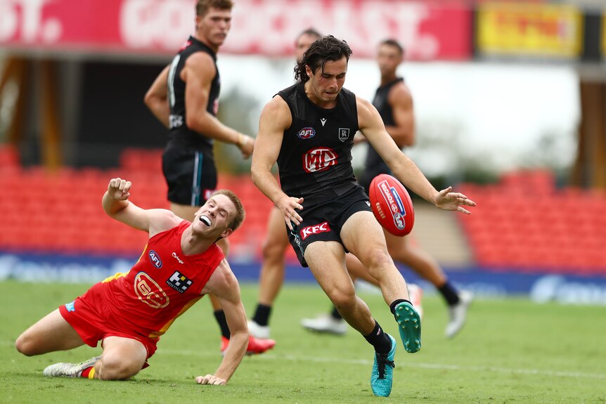 Josh Sinn kicks with his left foot as a Suns player falls behind him