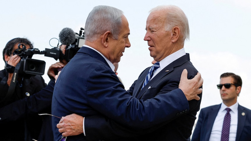 Netanyahu and Biden are pictured holding each other while being surrounded by cameras and security
