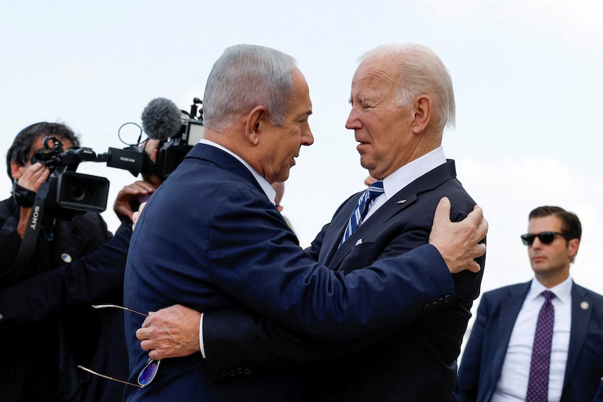 Netanyahu and Biden are pictured holding each other while being surrounded by cameras and security