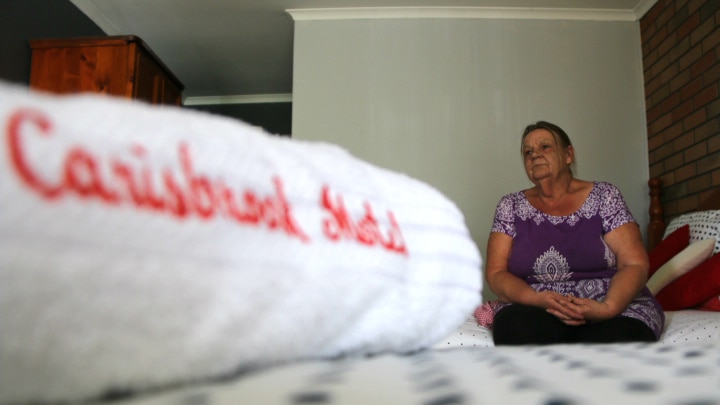 Carol Soewardie sits on the motel bed looking sad