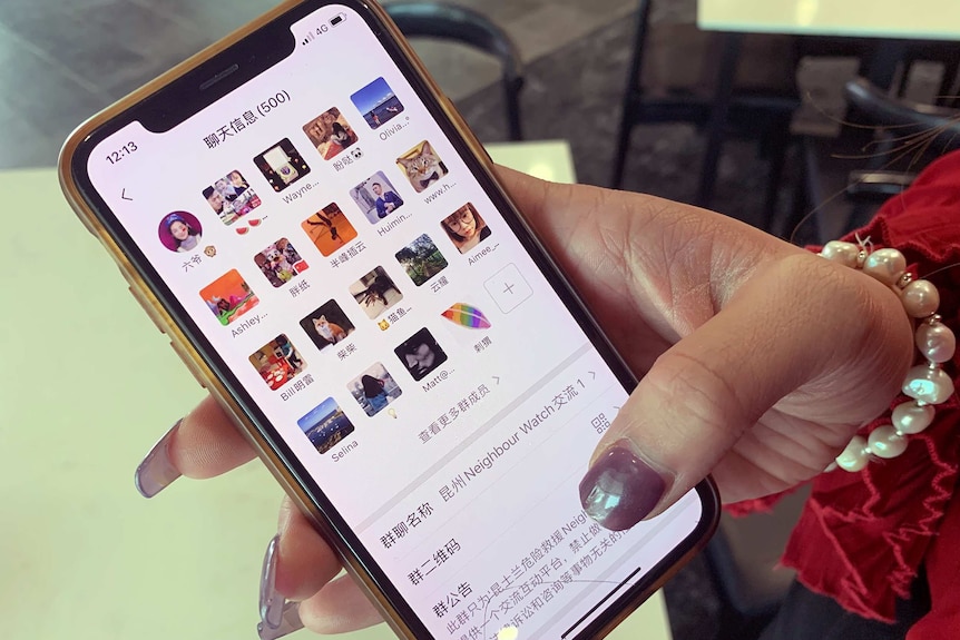 A hand holds a mobile phone showing the SOS-AUS group on the popular Chinese social media app WeChat.