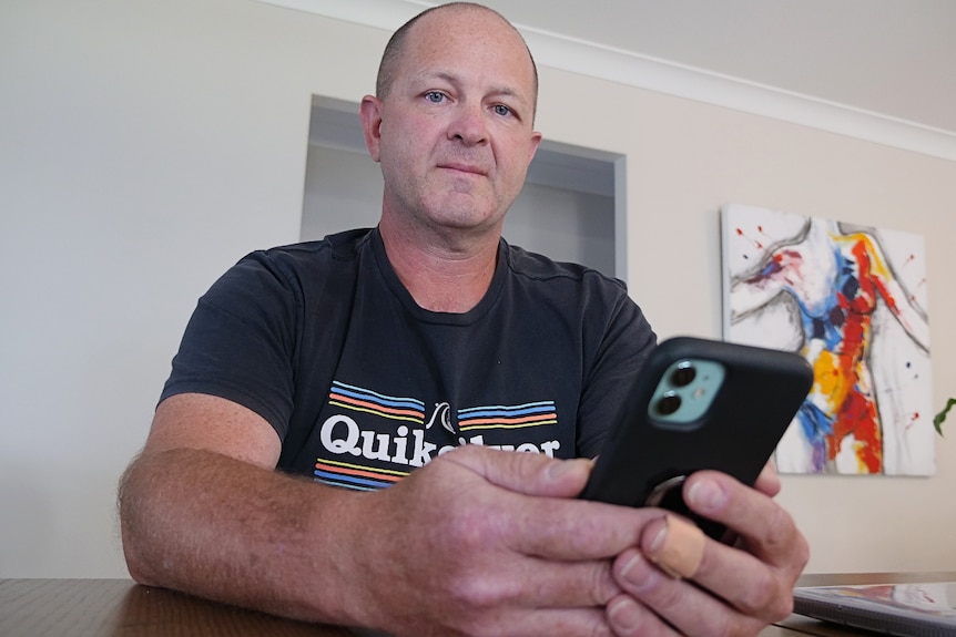 Man sitting at table holding a phone