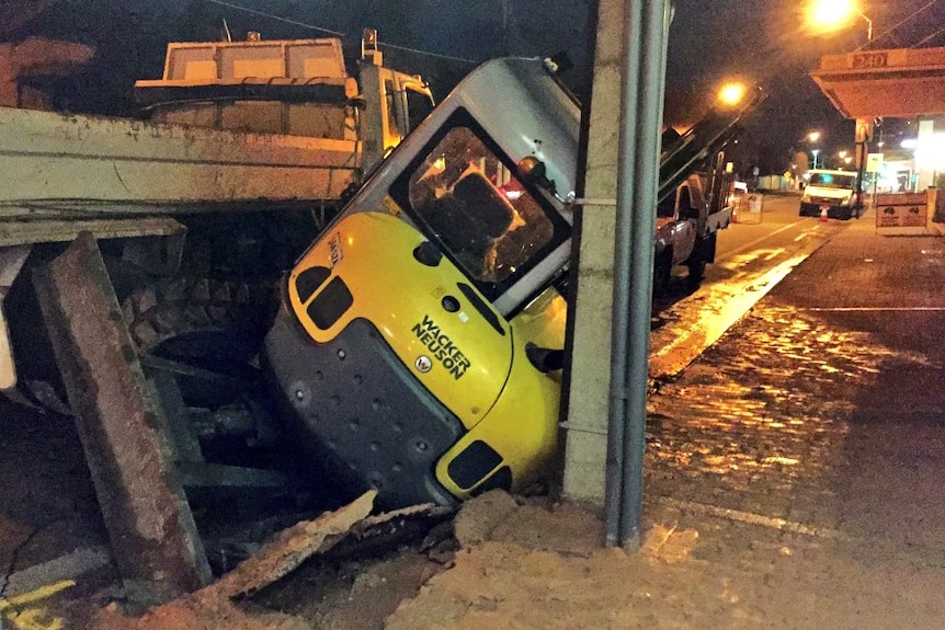 Digger stuck in a hole in the road