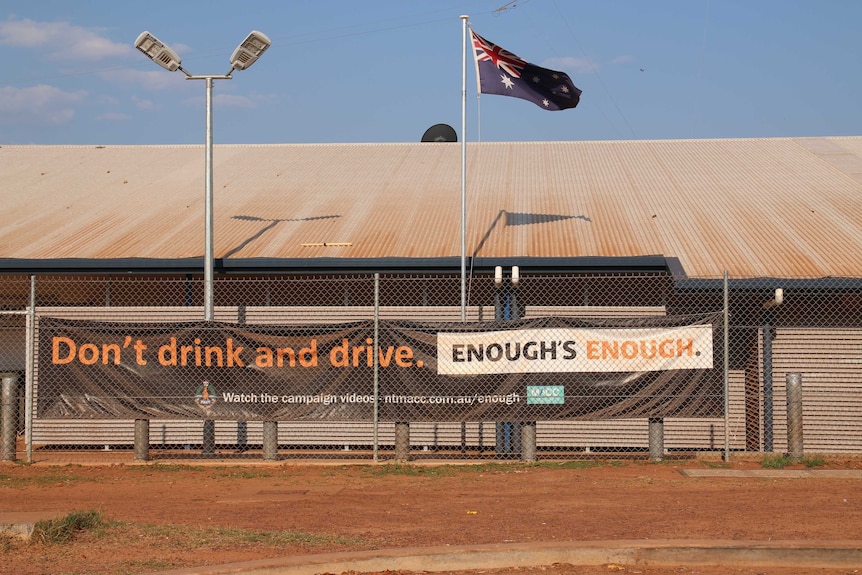A giant "don't drink and drive" poster is stuck to a fence outside the Wadeye police station