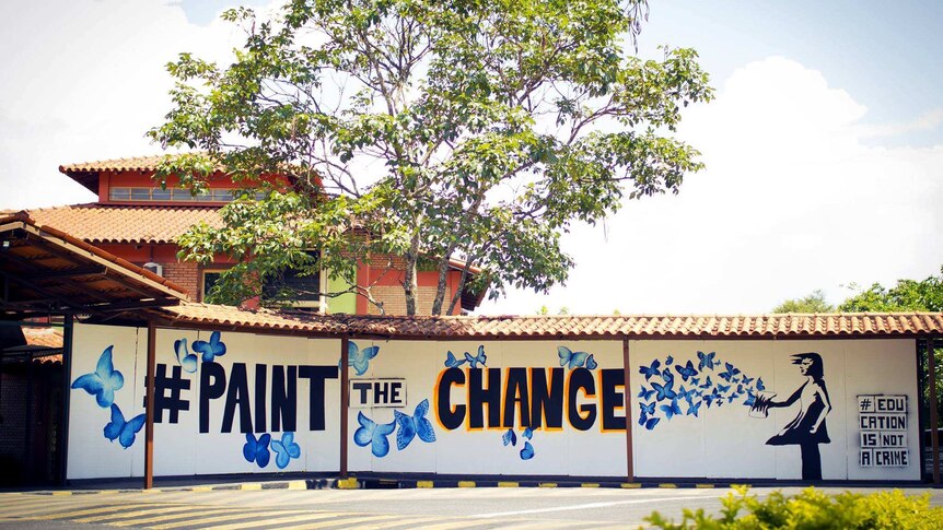 A mural saying 'paint the change' shows a girl releasing blue butterflies.