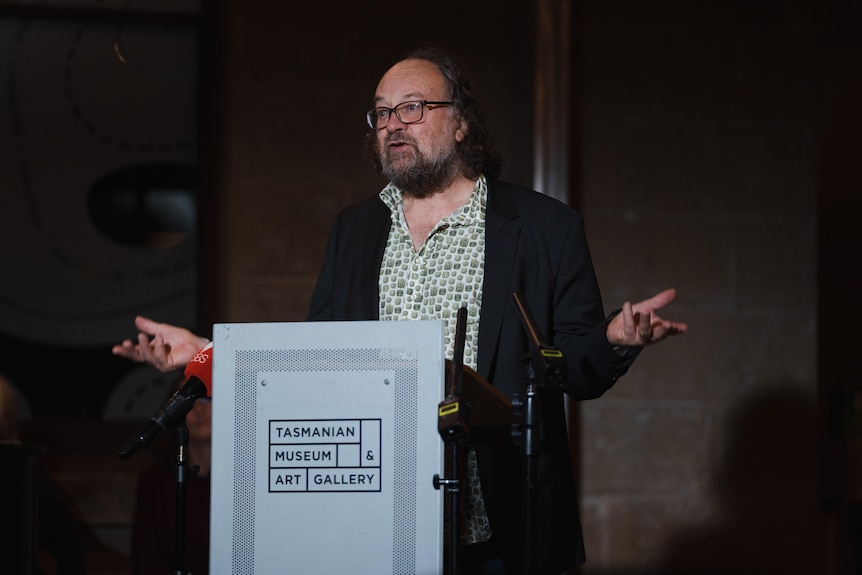  A man with a beard stands at a lectern