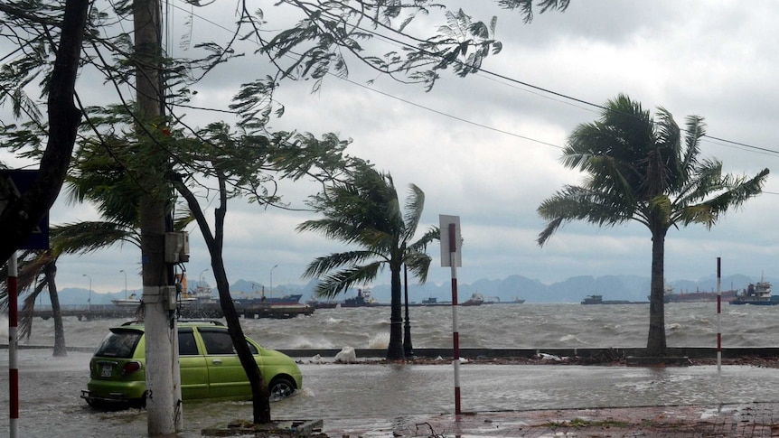 A taxi attempts to drive through a flooded road in Ha Long city, Quang Ninh province