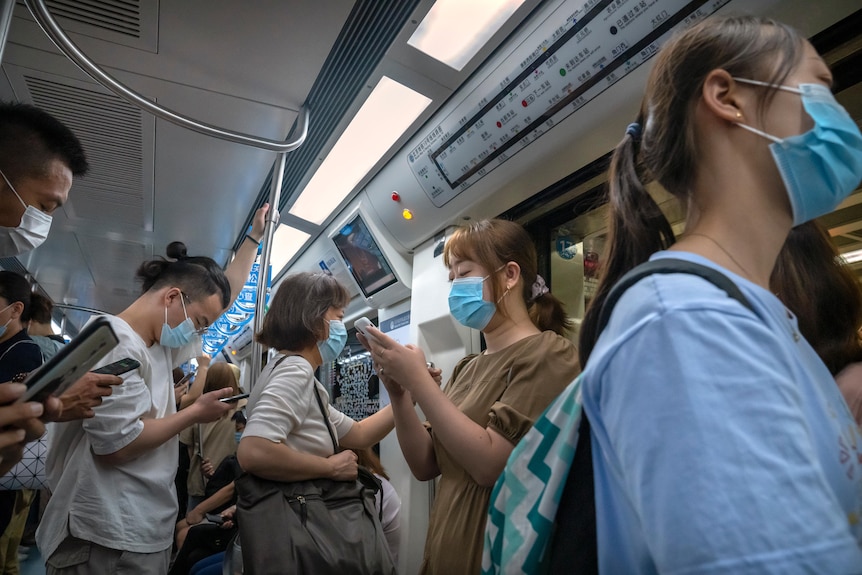 戴口罩以防止 COVID-19 的人登上北京拥挤的地铁列车