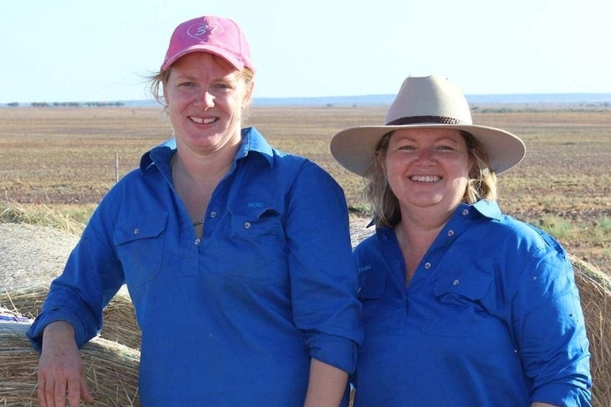 Nicki Blackwell and Tash Johnston stand by bales of hay.