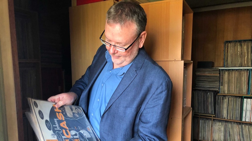 Dr Daryl Sparkes looks at some old Jonny Cash records, in the background is a cabinet filled with more records.