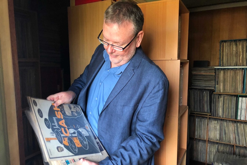 Dr Daryl Sparkes looks at some old Jonny Cash records, in the background is a cabinet filled with more records.