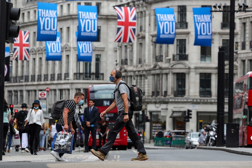 A man in a face mask crosses a street in London