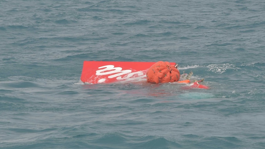 Indonesian divers float part of the AirAsia plane tail to the surface of the Java Sea