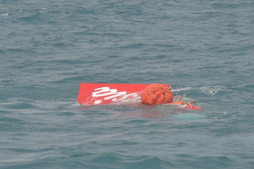 Indonesian divers float part of the AirAsia plane tail to the surface of the Java Sea
