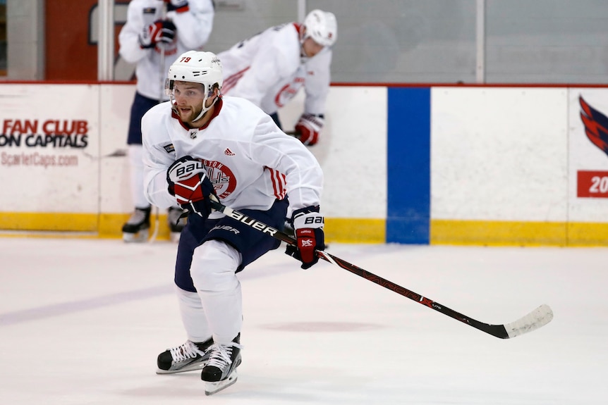 Nathan Walker an ice hockey player wearing a white uniform while skating and holding a stick.