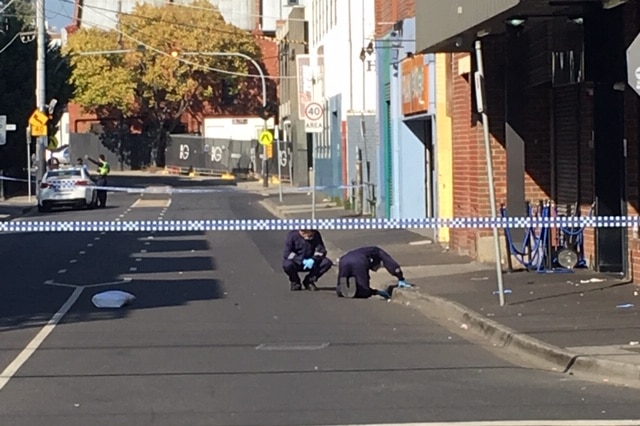 Forensic police search a drain at the scene.